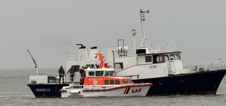 Mit dem Seenotrettungsboot WILMA SIKORSKI der DGzRS übernehmen die Seenotretter acht Menschen von einem festgekommenen Bestattungsschiff. Foto: Die Seenotretter – DGzRS